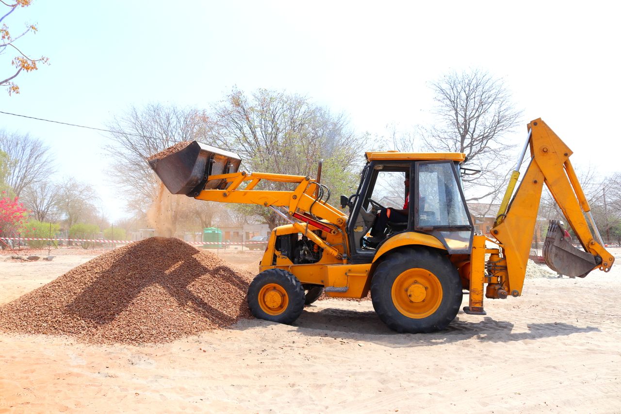 services-03 A yellow excavator moving gravel at an outdoor construction site during the day with clear skies.